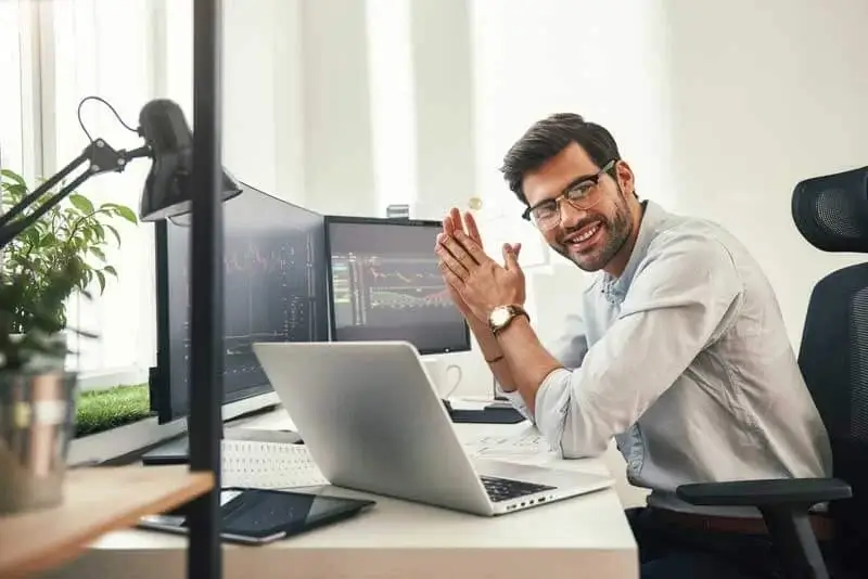 man sitting at desk in front of computer screens